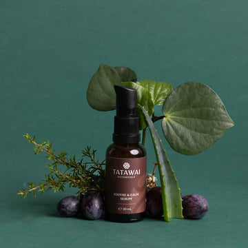 Tatawai skincare serum bottle with leaves and berries on a green background